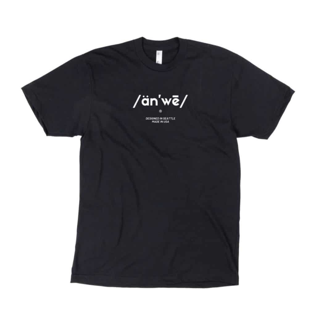 A black T-shirt featuring a minimalist design in white text. The front displays the phonetic pronunciation "/än'we/" with the phrase "Designed in Seattle, Made in USA" printed below.