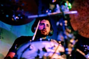 The drummer of The National Parks in focus, surrounded by vibrant, atmospheric lighting during a live show.