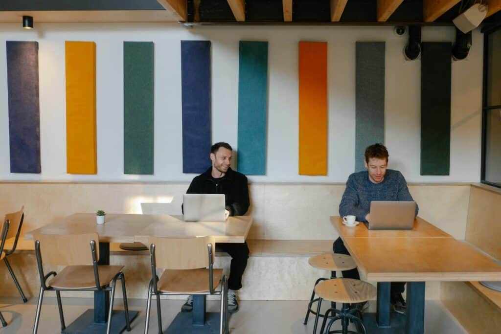 Two men sitting at tables  using laptop computers